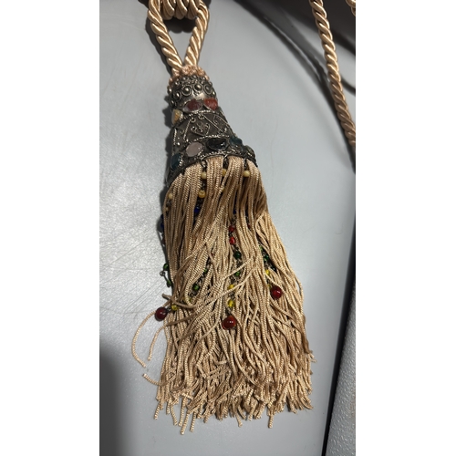 144 - Pair of cream twisted-cord curtain tiebacks, each terminating in an ornate metal mount set with colo... 