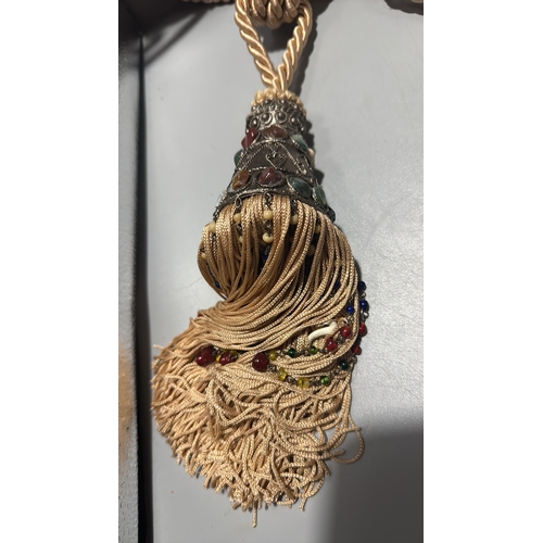 144 - Pair of cream twisted-cord curtain tiebacks, each terminating in an ornate metal mount set with colo... 
