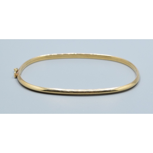 137 - 9ct gold oblong bangle with spring closing and safety clip and embossed pattern to one edge  6.3x5.3... 
