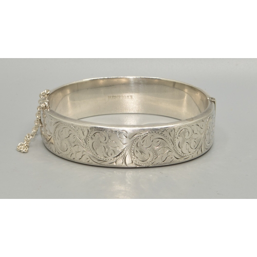 54 - 925 silver ladies bangle with embossed decoration to one side, with safety chain attached 6cm intern... 