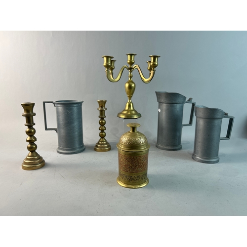 317 - A collection of pewter jugs and brass candle holders and a tea caddy.