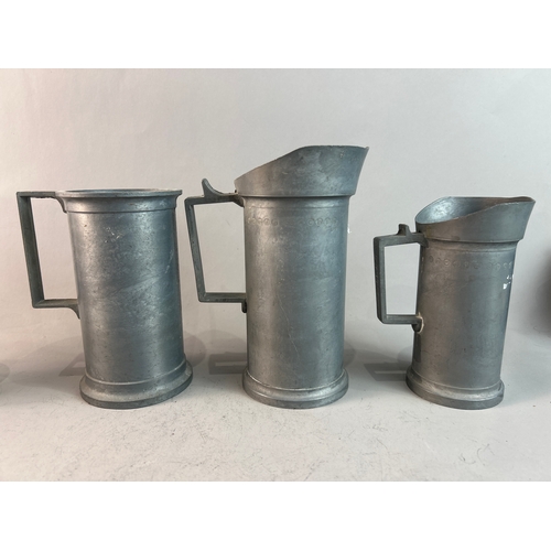 317 - A collection of pewter jugs and brass candle holders and a tea caddy.