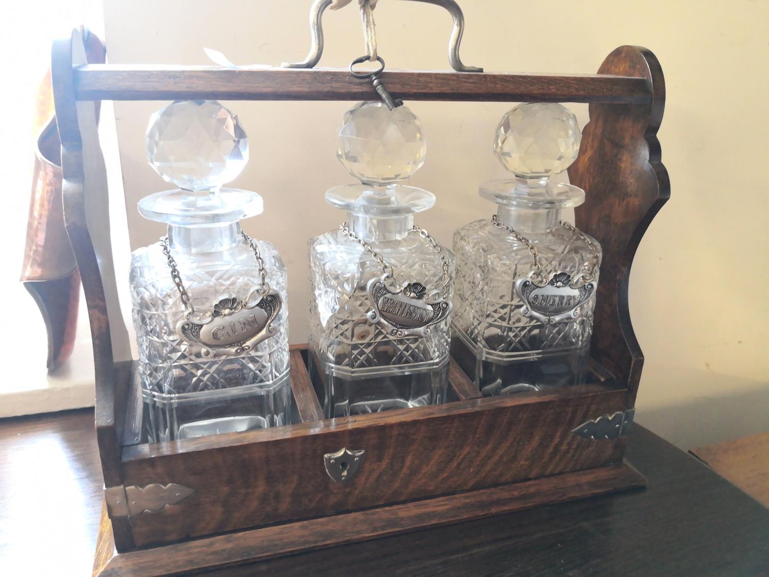 An oak tantalus with 3 decanters & labels