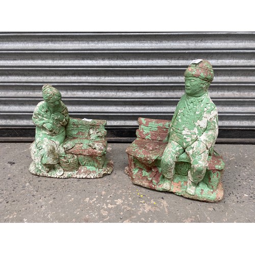 170 - Two stone ornaments of an older couple sitting on benches 36cm tall.