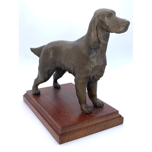 1076 - Bronzed coloured figure of a dog on a wooden stand.