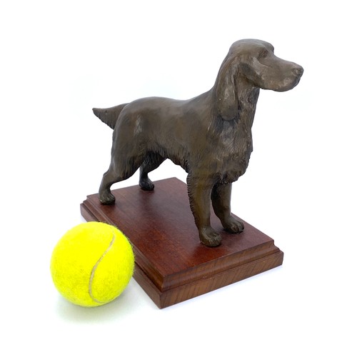 1076 - Bronzed coloured figure of a dog on a wooden stand.