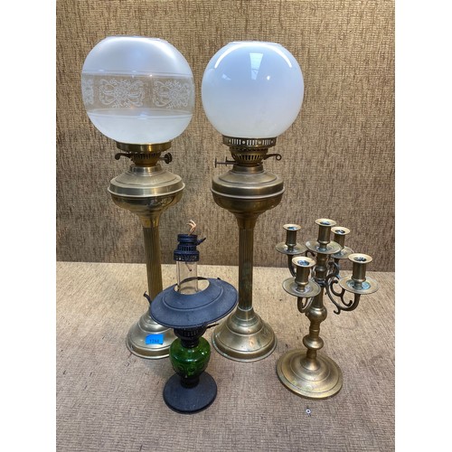 11 - A pair of brass column oil lamps, a green glass oil lamp and a five-fork table candle stick.