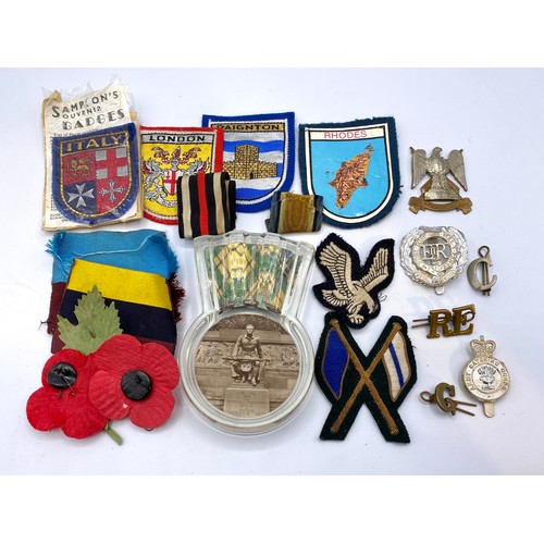 656 - Selection of cap badges, shoulder titles cloth badges, ribbons  DZ patches and a Scottish paperweigh... 