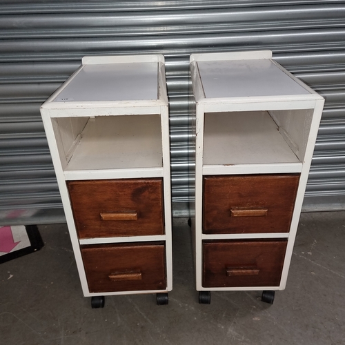 115 - A pair of bedside drawers each on wheels and with two drawers.