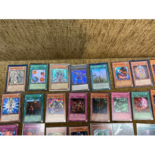 734 - Approximately 100 yu-gi-ho trading cards including an range of different rarity of cards.