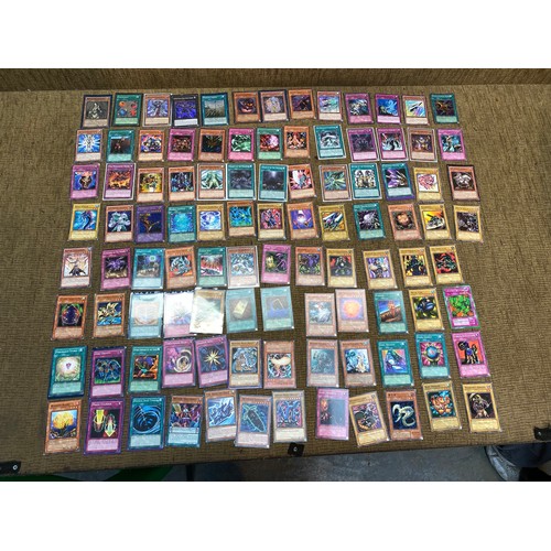 734 - Approximately 100 yu-gi-ho trading cards including an range of different rarity of cards.