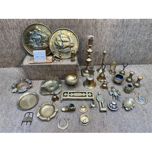 533 - A selection of brass items including a candlestick and two wall plaques.