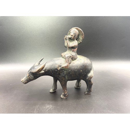 962 - Asian bronze of a boy plating a flute on a water buffalo.