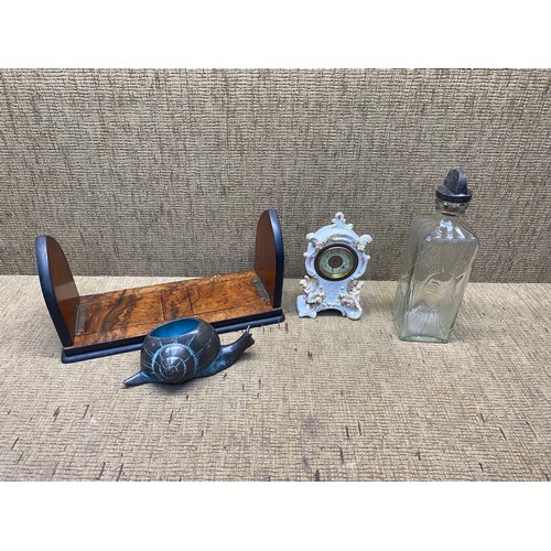 597 - burr walnut Wooden bookends, French ceramic clock, brass snail and a glass whiskey bottle.