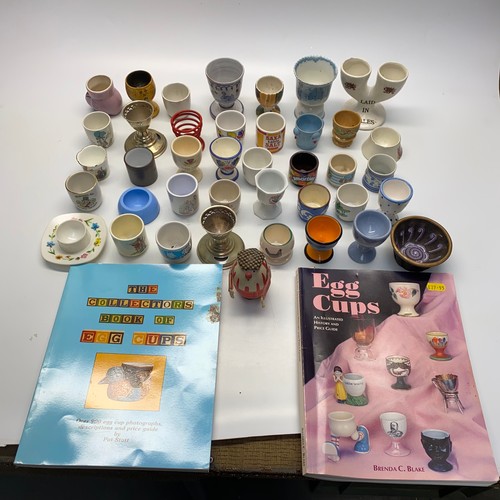 803 - Large collection of novelty egg cups and two books.