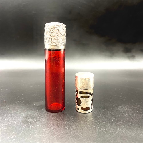 702 - Two red glass powder/perfume bottles with silver lids.