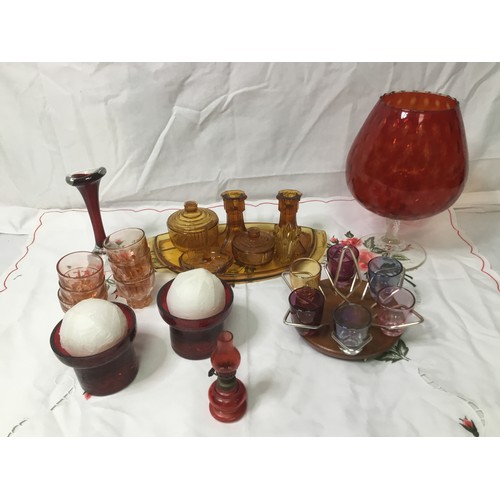 502 - A selection of coloured glass including dressing table set, set of shot glasses on stand and candles