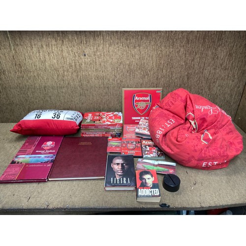 62 - Collectible merchandise of arsenal fc including bean bag, pillow, wallet, and selection of books.