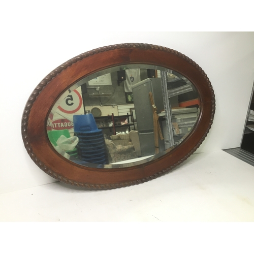 1072 - Heavy oval wooden framed mirror with bevelled edge