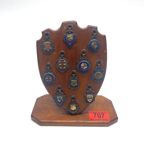 707 - Eleven sterling silver football fobs mounted on a wooded stand.