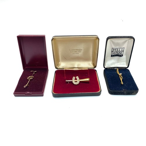 891 - Three yellow metal brooches/tie pins two with horseshoe design