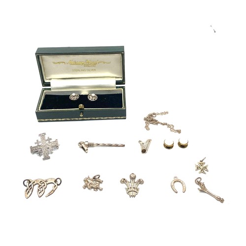 1021 - A collection of silver charms, along with a brooch, a necklace, and silver cufflinks.