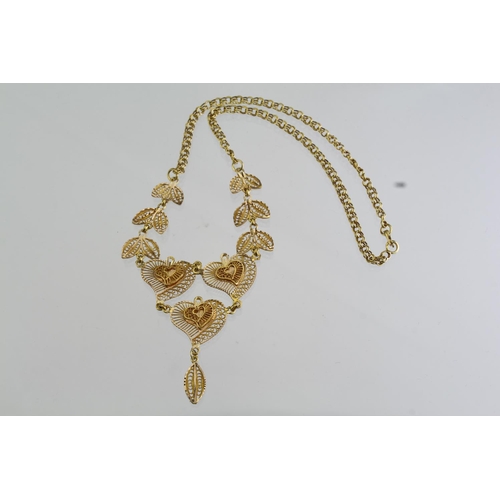 275 - Tests as over 14ct yellow gold necklace showing three hearts and leaves in filigree work, on a doubl... 