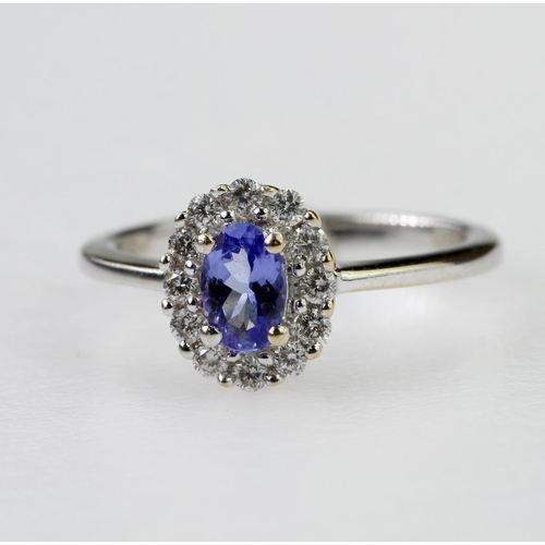 112 - 18ct white gold cluster ring set with a central oval tanzanite measuring approx. 6mm x 4mm, surround... 