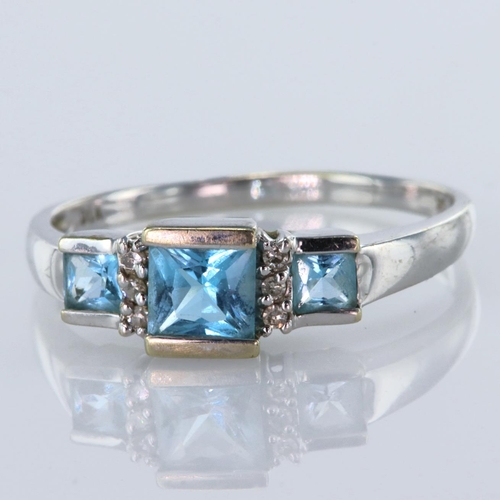 94 - 9ct white gold ring set with three graduated princess cut blue topaz with six diamond accents totall... 