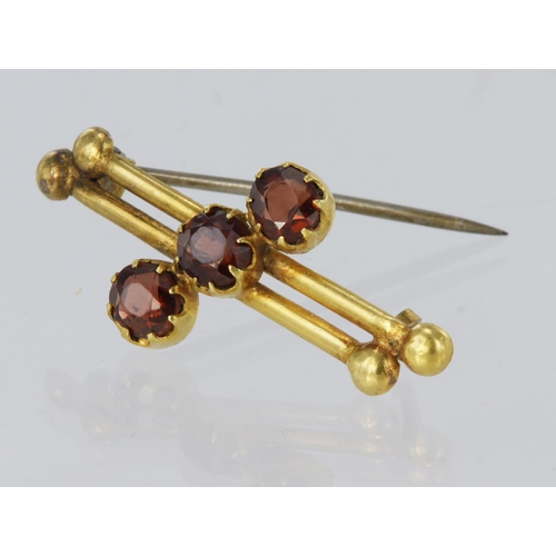 141 - 18ct yellow gold double bar brooch set diagonally with three round garnets measuring approx. 5mm dia... 