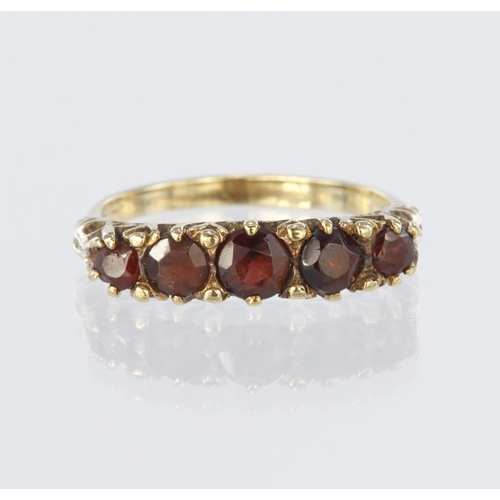 15 - 9ct yellow gold carved head ring set with five graduated round garnets ranging from 4mm x 2,5mm diam... 