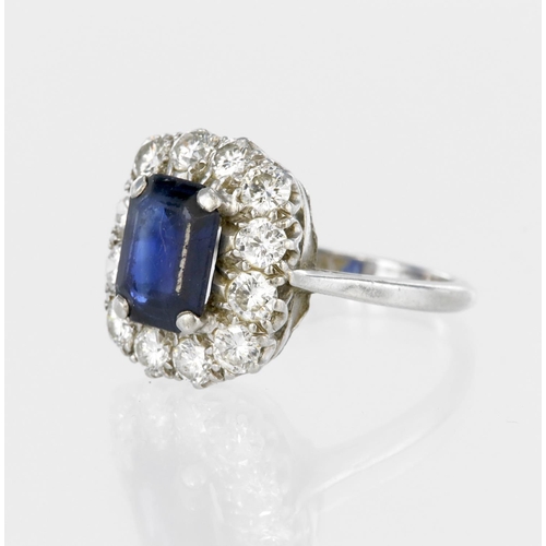 56 - Platinum cluster ring set with a central rectangular step cut sapphire measuring approx. 9mm x 7mm, ... 