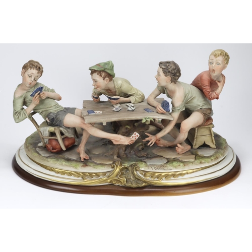 938 - Capodimonte. A large figural display 'The card cheats', depicting a group of children sat around a t... 