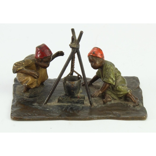 1073 - Cold painted bronze depicting two Middle-Eastern boys seated around a fire with a hanging cooking po... 