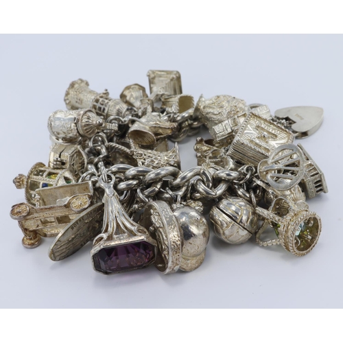 244 - Silver / white metal charm bracelet with a large number of charms attached. Total weight 228.7g