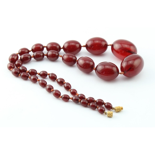 258 - Amber ? bead necklace, comprising thirty-eight graduated polished oval cherry amber / bakelite ?bead... 