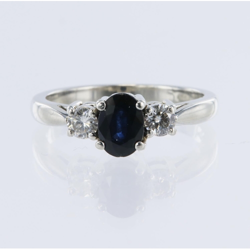 12 - Platinum trilogy ring, set with one oval mixed cut dark blue sapphire approx weight 1.05ct, flanked ... 