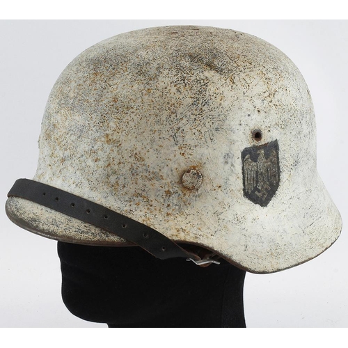 379 - German WW2 single decal Army helmet painted with white snow camo complete with liner and chin strap.