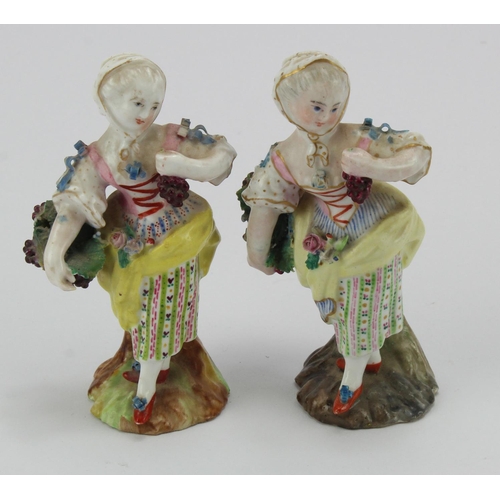 126 - Two Meissen figures of a lady carrying a basket of grapes, on a rocky base, blue crossed swords to b... 