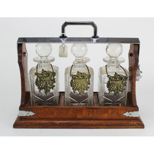 1059 - Oak tantalus, housing three cut glass decanters with stoppers (one decanter with loss), height 30 ap... 