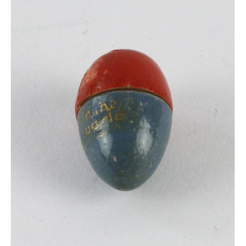 1081 - Smallest doll In the World. Blue and red wooden egg with title in gold paint. Complete with doll ins... 