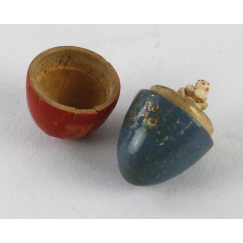 1081 - Smallest doll In the World. Blue and red wooden egg with title in gold paint. Complete with doll ins... 