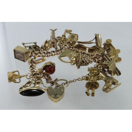 544 - 9ct / Yellow metal charm bracelet with a good selection of charms attached. Includes many better typ... 