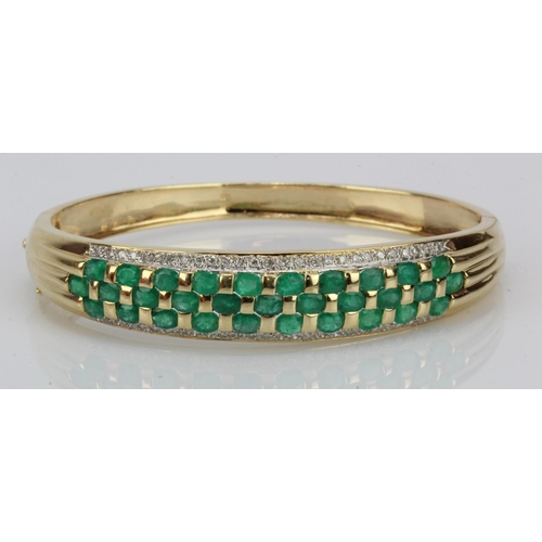 928 - Yellow gold (tests 14ct) diamond and emerald set bangle, set with thirty-one approx. 4mm x 3mm emera... 