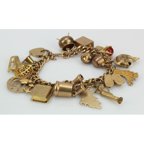 962 - 9ct / Yellow metal charm bracelet with a good variety of charms attached. Total weight 53.7g