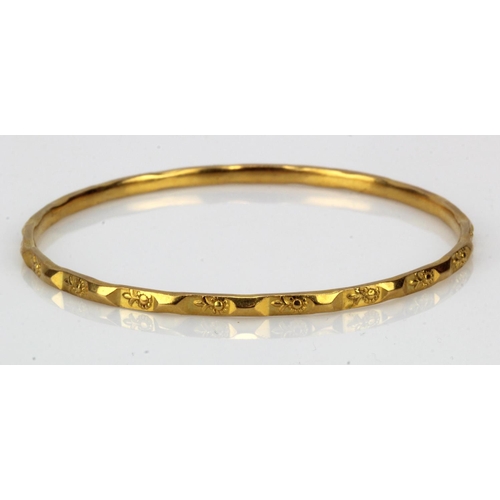 985 - Yellow gold (tests 22ct) solid bangle, floral motif pattern, width approx. 2.8mm, inside diameter 58... 