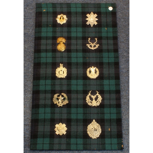 1550 - Scottish cap badge collection mounted on an old tartan cloth  (10)