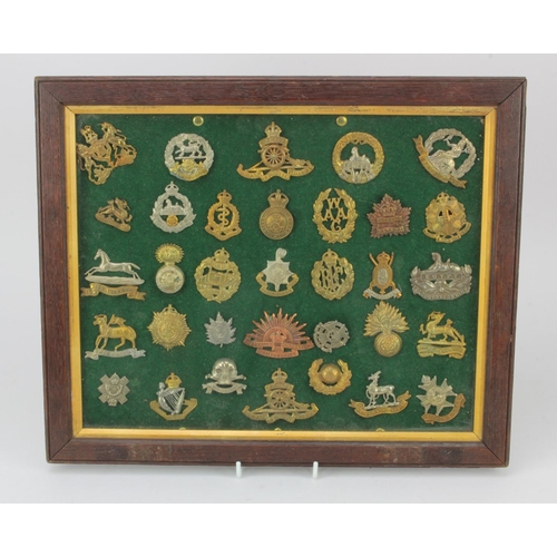 526 - Cap badges housed in an old glazed frame, various Regts  (33)