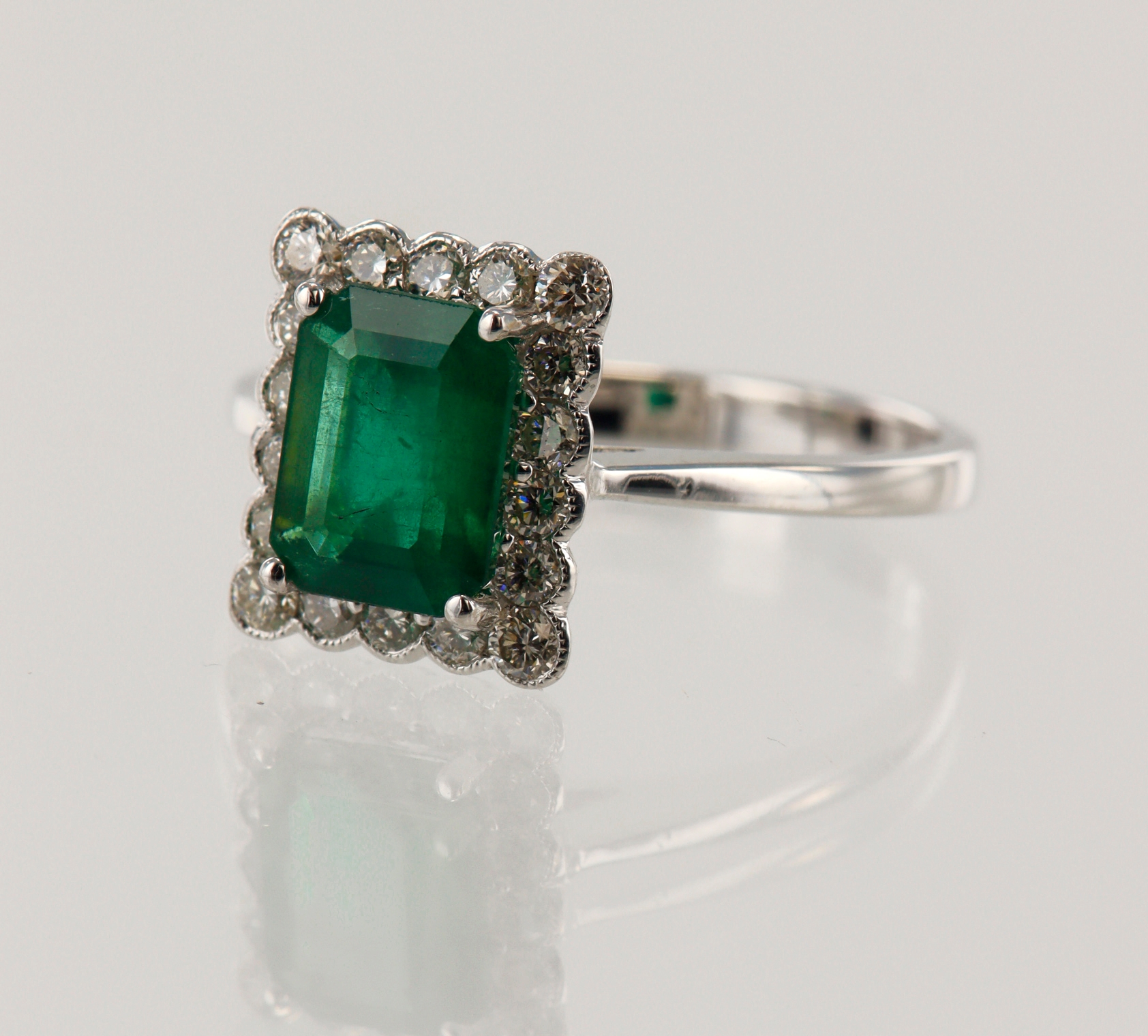 White gold (tests 18ct) diamond and emerald cluster ring, emerald-cut ...