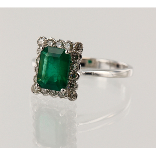 180 - White gold (tests 18ct) diamond and emerald cluster ring, emerald-cut emerald measures 7.8mm x 6mm, ... 